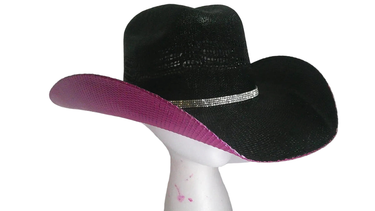 A black woven cowboy hat with a bright pink underside on the brim and crown, accented by a silver rhinestone band, displayed on a white mannequin head.